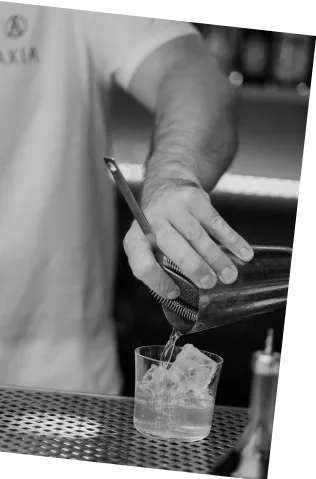 Black and white picture of Axia Spirit White Negroni Cocktail being prepped by a man