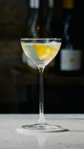 Axia Martini Cocktail on a table with bottles in the background