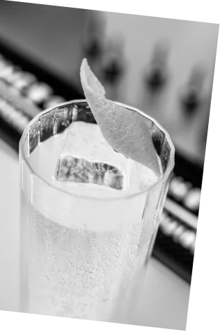 Black and white picture of an Axia Greek Mastiha Spirit and London Essence Lemonade Collins Cocktail on a bar