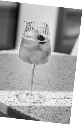 Black and white picture of an Axia Greek Mastiha Spirit and red wine Heliodoro Cocktail with Joia Battersea on a table