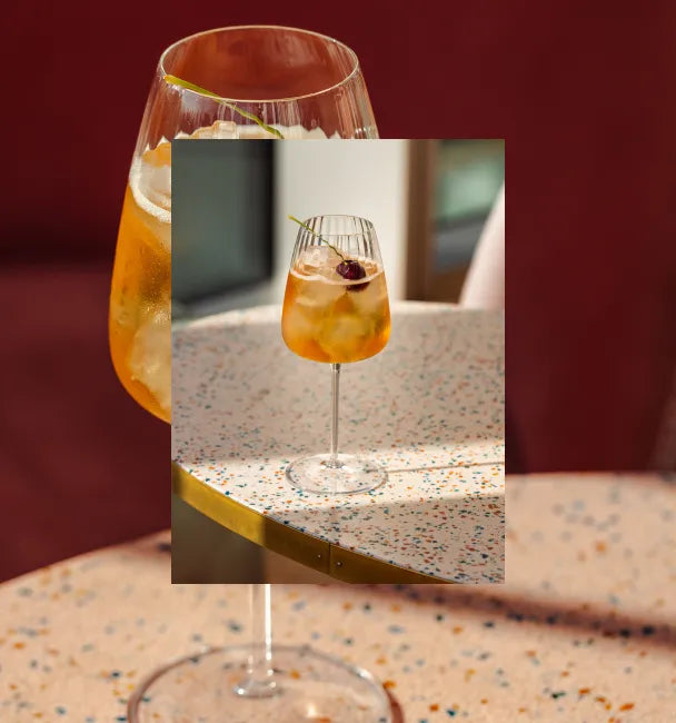 Axia Greek Mastiha Spirit and red wine Heliodoro Cocktail with Joia Battersea on a table with a secondary picture in the background of another Heliodoro cocktail